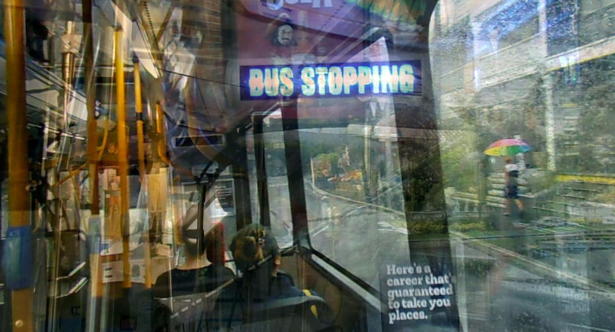 image of a bus window shadow with the text bus stopping in the relfection