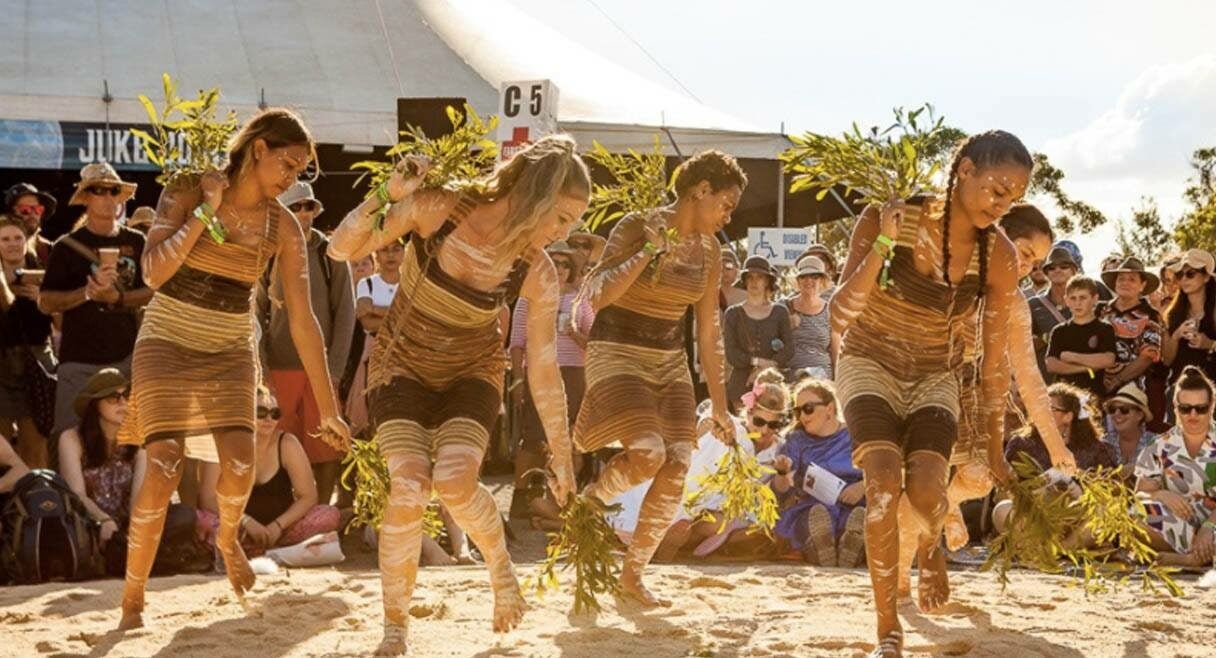 image of a group of indigenous woman dancing in a circle with leaves