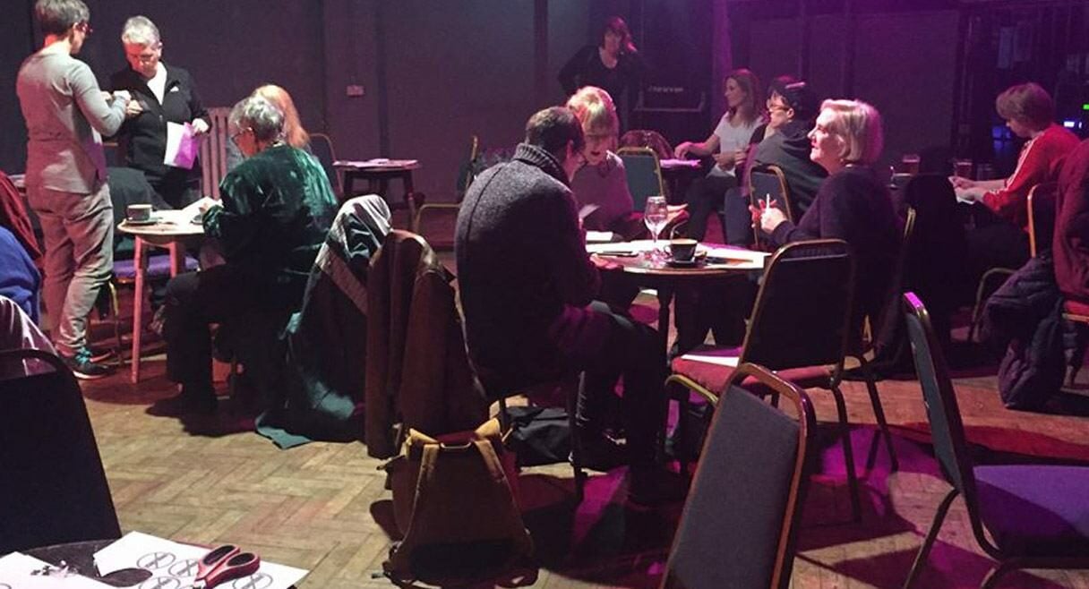 image of a cafe with purple lighting and people sitting at round tables in a room