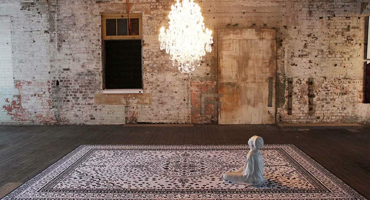 image of a young body sitting on a rug shrouded in white sitting under a chandelier