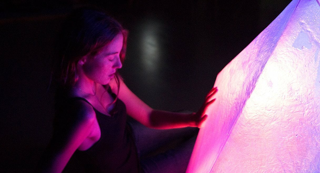 image of a girl in pink lighting touching a large plastic object