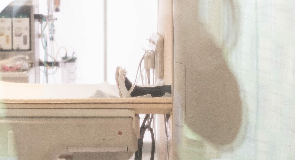 image of a young girls feet in black stockings white shoes sticking outside a hospital scanning machine