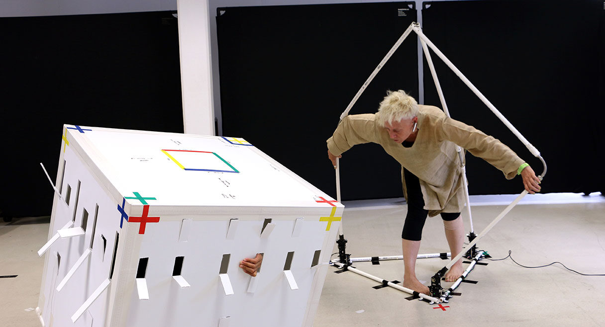 image of a white box and a man standing beside it with arms and legs suspended