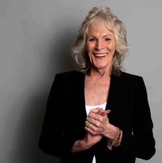 Sandra standing in front of grey background, hands clasped